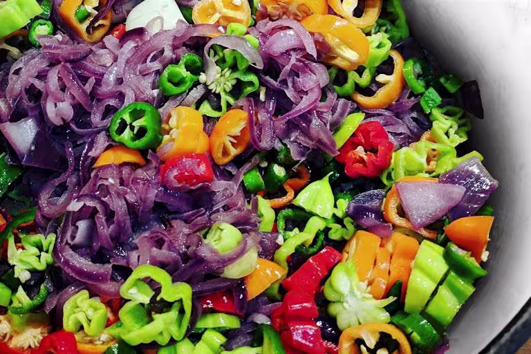 An iridescent array of chilies, onions, and garlic, slowly sweating over a low heat